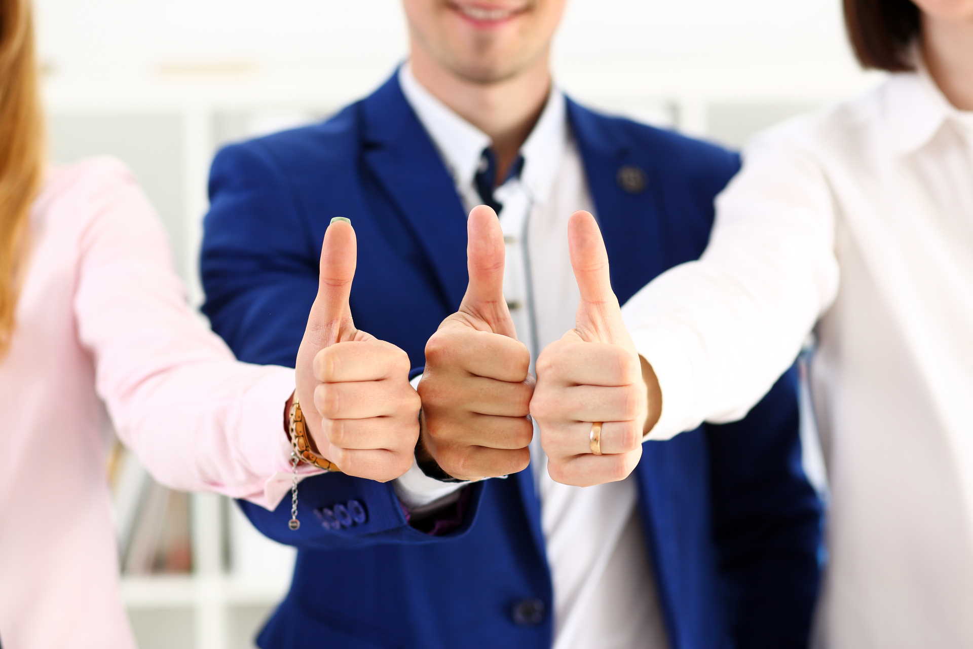 Three smiling team members giving a thumbs up.